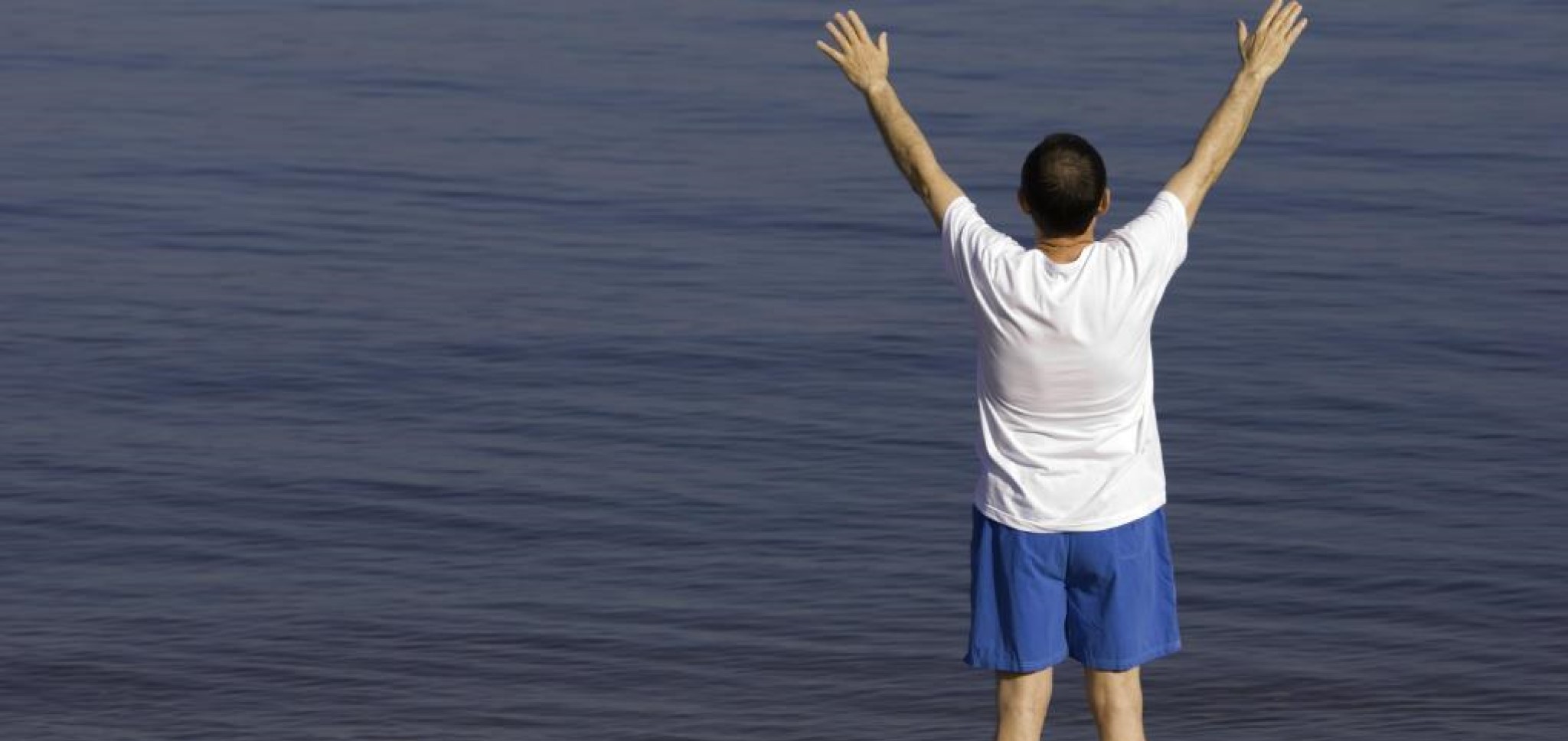 Billede af en rask mand der strækker sig med udsigt til havet