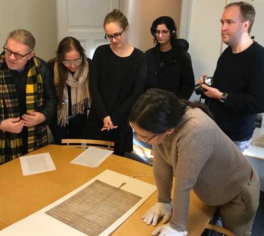 AntCom-holdet er på besøg på Herlufsholm Skole. Anna Charlotte Epple og Baharan Pourahmadi-Meibodi står henholdsvis til venstre og højre i døråbningen. På bordet foran dem ligger et middelalderfragment