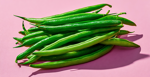 Grønne bønner i en bunke på lyserød baggrund