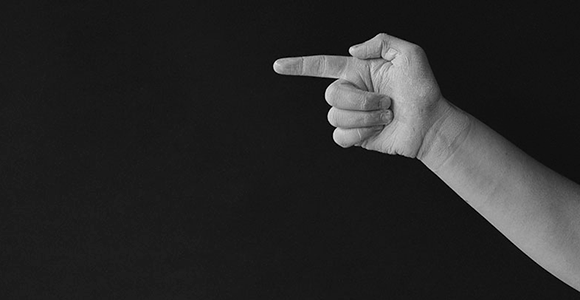 Billede af en knyttet hånd med en finger, der peger i venstre retning. 