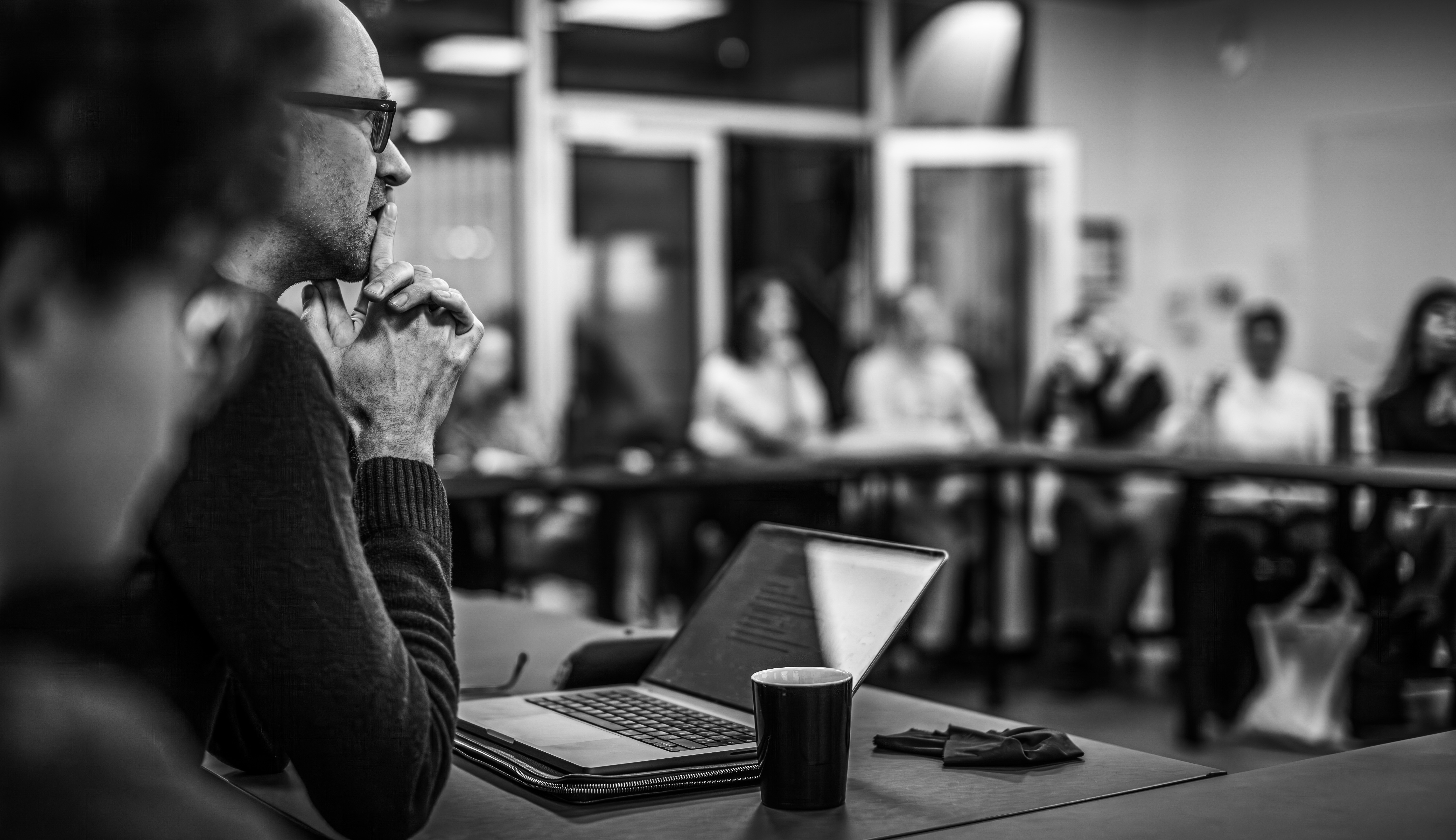 En gruppe af DIAS-forskere sidder i et seminarrum. En ser tænksom ud med foldede hænder. 