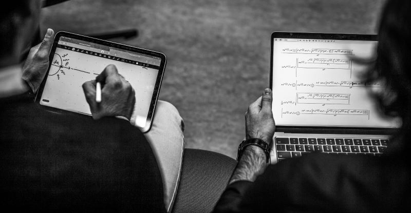 two people seen from behind working on tablets