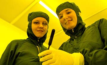 Oksana Zenina and Roana de Oliveira-Hansen looking at a glaswafer in the cleanroom.