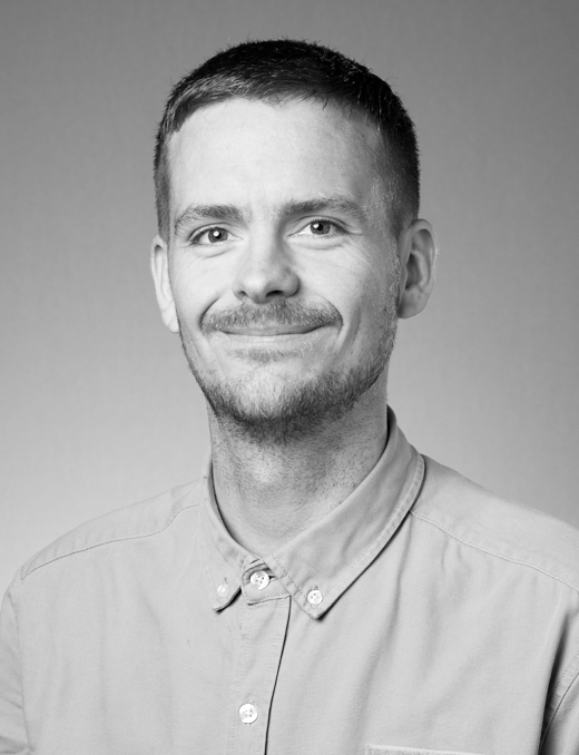 Black-and-white portrait of a smiling man in a button-up shirt Black-and-white portrait of a smiling man with short hair and light facial hair wearing a button-up shirt.