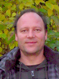 Head-and-shoulders outdoor portrait of Christoph Flamm in front of leafy foliage.
