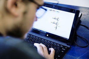Person using a laptop with a technical diagram visible on the screen.