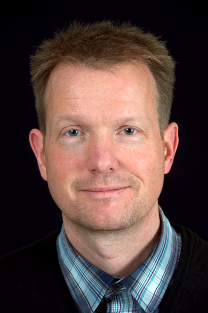 Head-and-shoulders portrait of Rolf Fagerberg in a striped shirt and tie against a dark background.