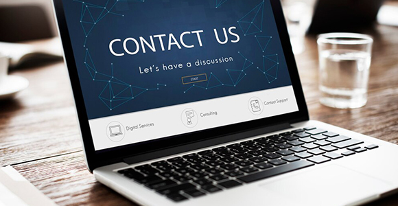  A laptop on a wooden table displaying a "CONTACT US" page