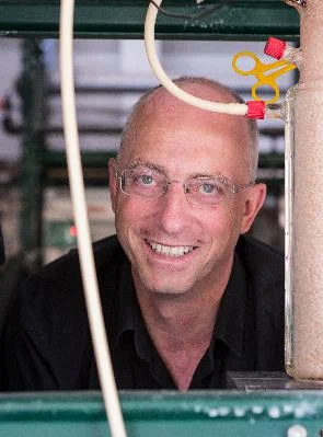 Mark van Loosdrecht portrait in an industrial setting Mark van Loosdrecht smiling in an industrial or laboratory setting with pipes and equipment in the foreground.