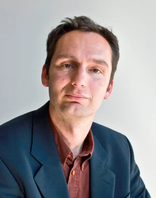Portrait of Peter Verburg Portrait of Peter Verburg in a dark blazer and reddish shirt against a light background.