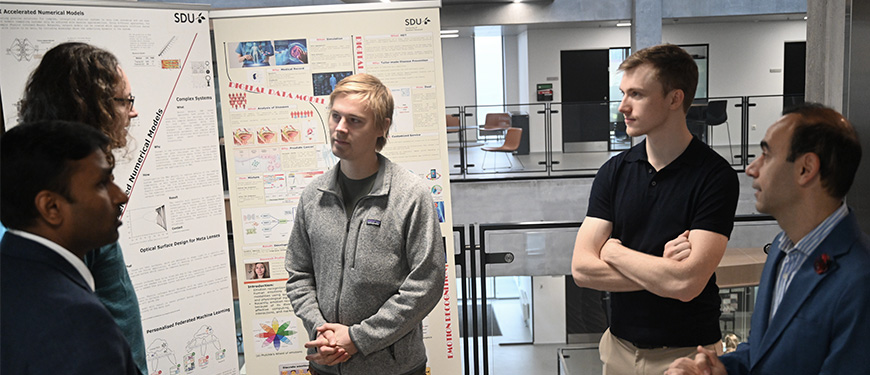 Researchers discussing in front of roll-ups