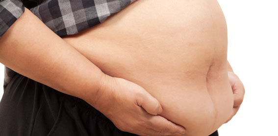 Nærbillede af gravid mave med hænder placeret under maven.