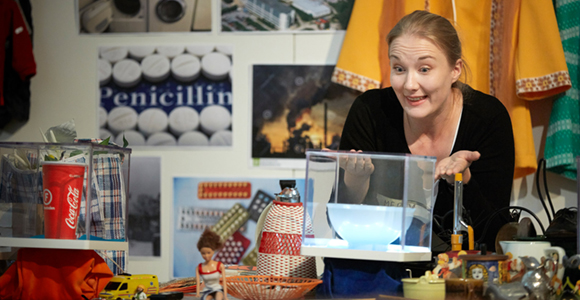 Picture of Merja Ryöppy standing behind a table with historical and contemporary objects. 