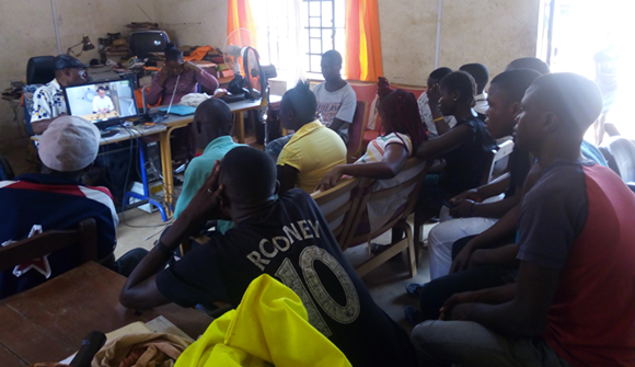 Picture of students at a business school in Sierra Leone watching Dylan Cawthorne’s instructional video before they start producing masks.