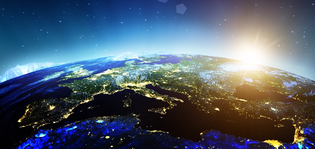 Europa set fra rummet om natten med lysende byer og solopgang ved horisonten.