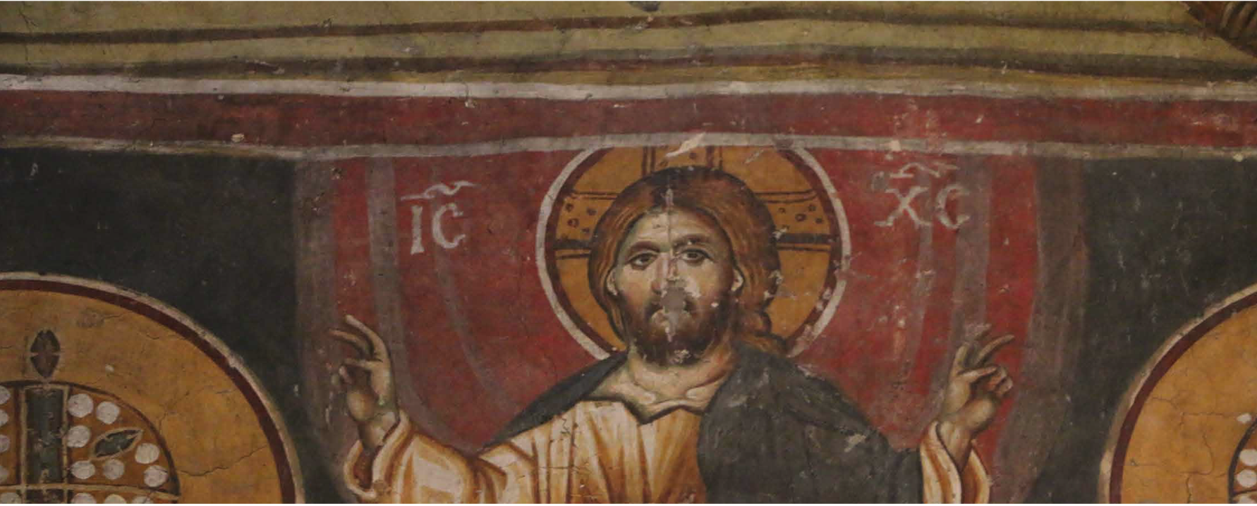 Close-up of a Byzantine fresco depicting Christ with a cross halo, raised hands, and the inscriptions “IC” and “XC”.