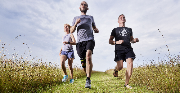 Foto af tre løbere på en græsmark