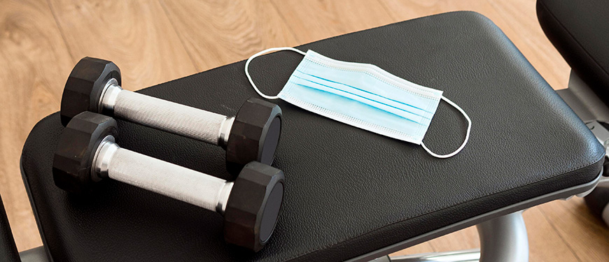 To håndvægte og et mundbind på en træningsbænk