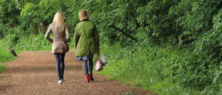 To kvinder går tur på sti i grøn skov