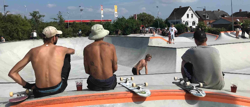 Unge sidder med ryggen til ved skateboard rampe