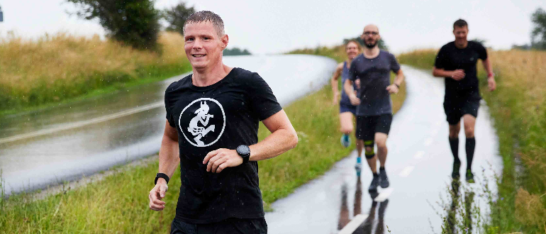 En flok løbere i regnvejr - den første smiler
