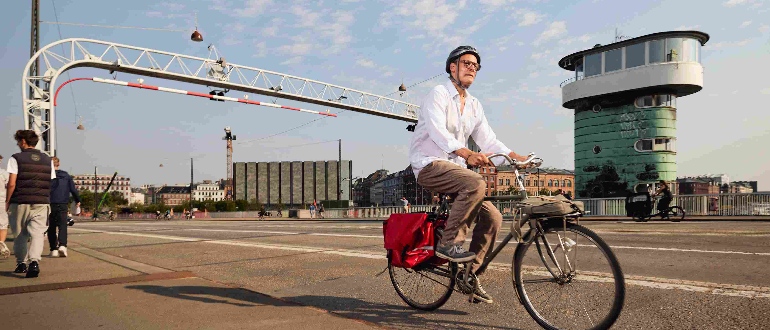 Mand cykler over bro i København - på vej til arbejde