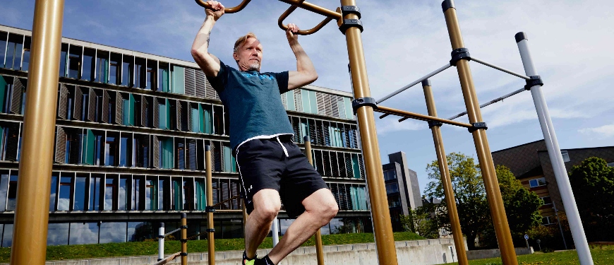 Mand træner i fitnessredskab udenfor boligblok