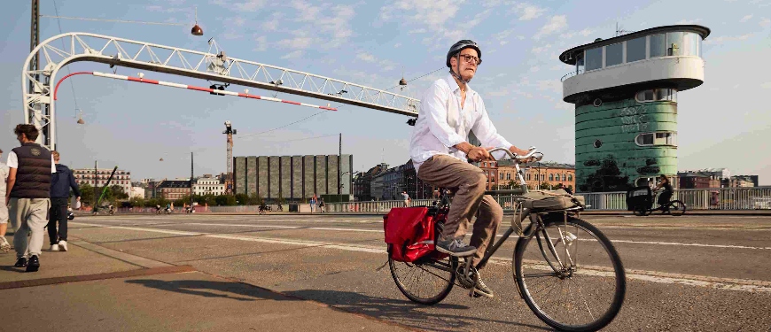 Mand cykler hen over bro på vej til arbejde