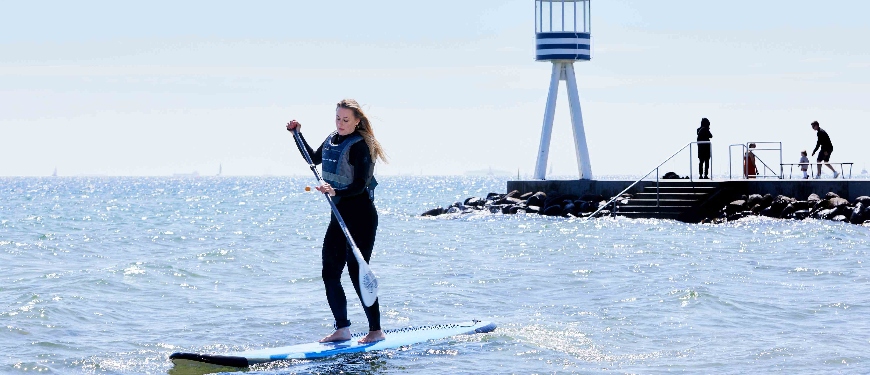 Kvinde står på SUP-board