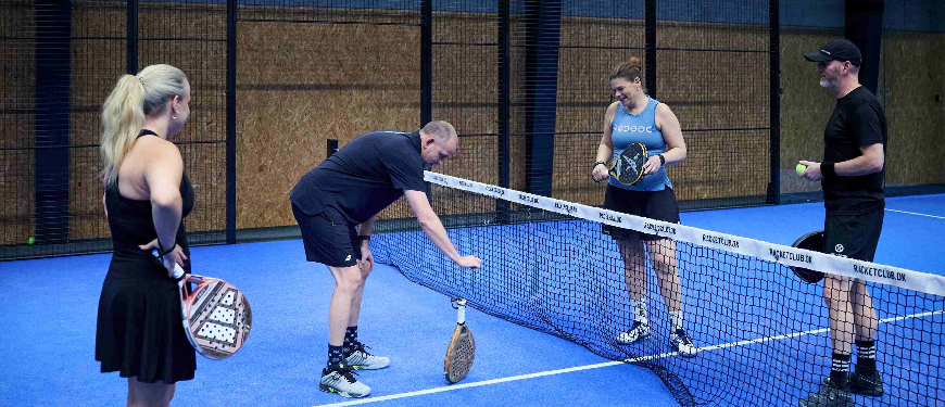 Fire voksne spiller padel på padelbane