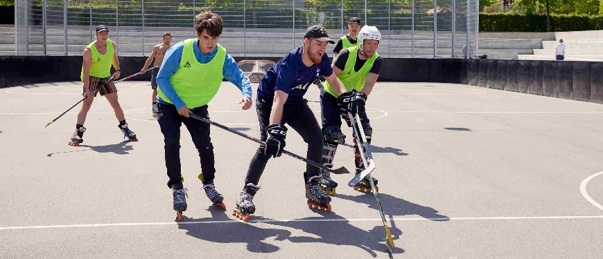 Unge mænd spiller rullehockey på baneanlæg