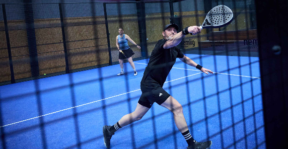 To voksne spiller padel på en padel-bane