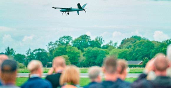Crowd watching a drone flight demonstration Blurred spectators watching a drone flying over a field.