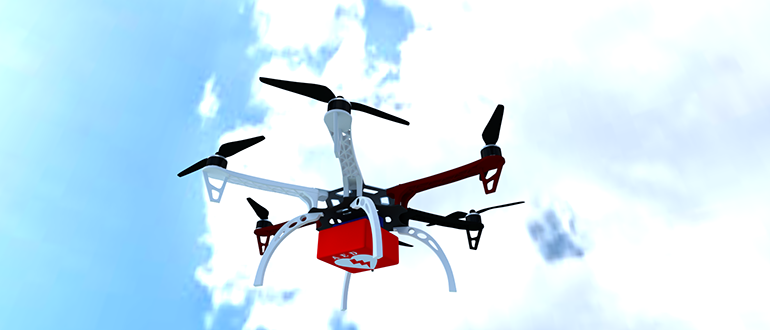 Quadcopter drone with a red payload flying in a bright cloudy sky.
