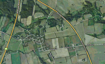 Satellite map of a rural landscape with farmland parcels, small clusters of buildings, and roads.