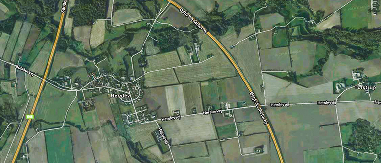 Satellite map of rural farmland and roads around Herslev with labels including "Herslev", "Herslevvej", "Bøstrup", "Tolstrup", and "Østjyske Motorvej".