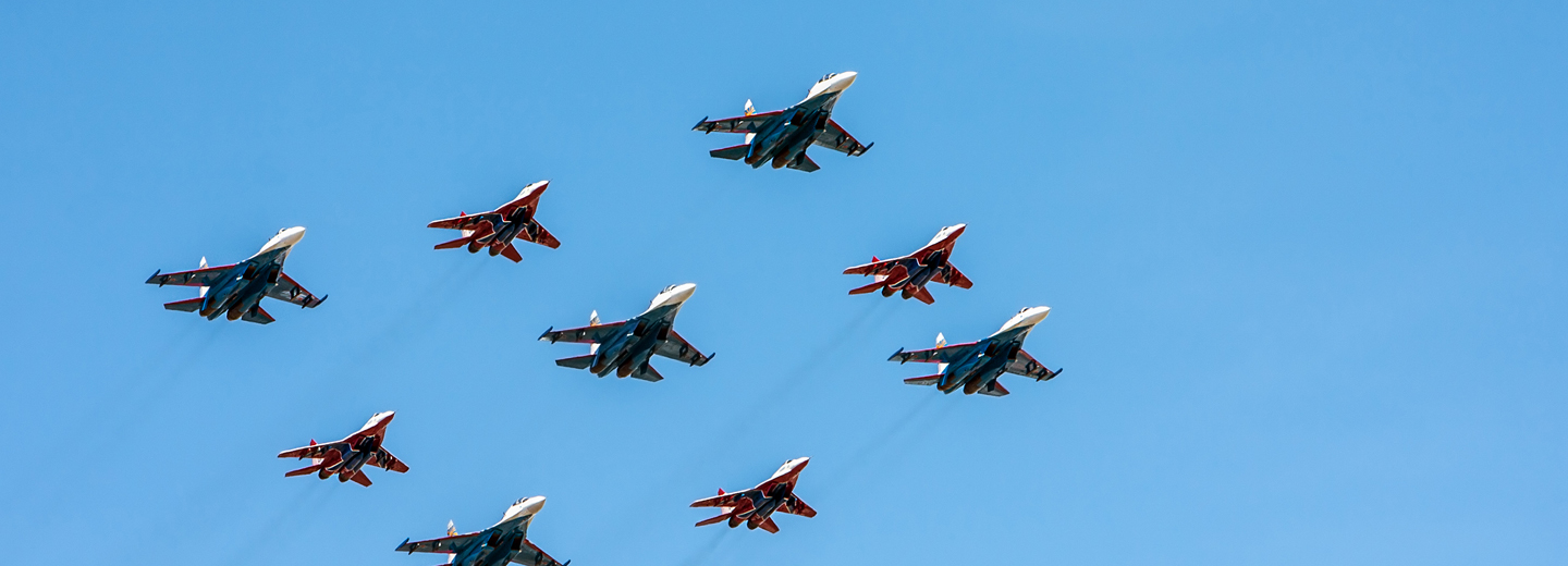 Syv kampfly i formation på en skyfri blå himmel.