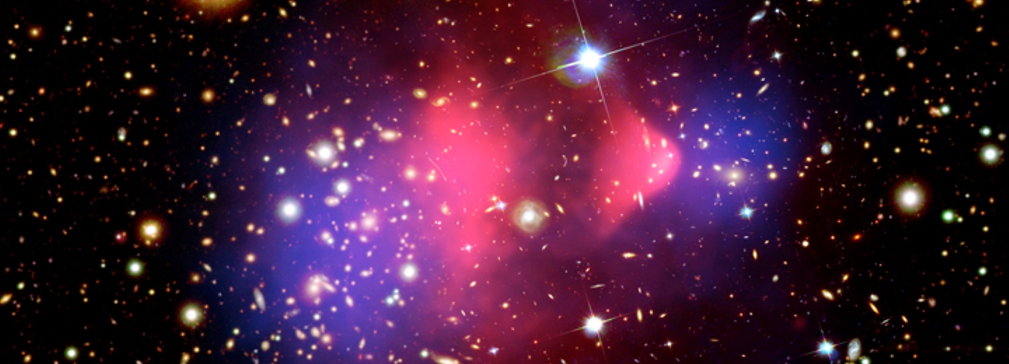 Astronomisk rumscene med mange stjerner og galakser samt røde, pink og blå skyer i midten.