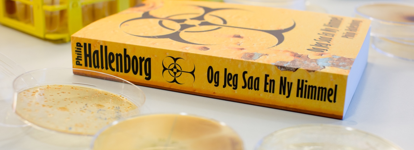 Gul bog med teksten "Philip Hallenborg" og "Og Jeg Saa En Ny Himmel" på et bord med petriskåle.