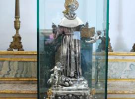 Religiøs statue i glasmontre i et kirkeinteriør.