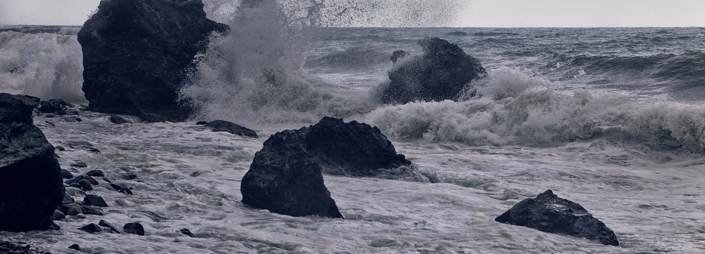 Powerful storm surf striking dark rocks on a rocky coast.