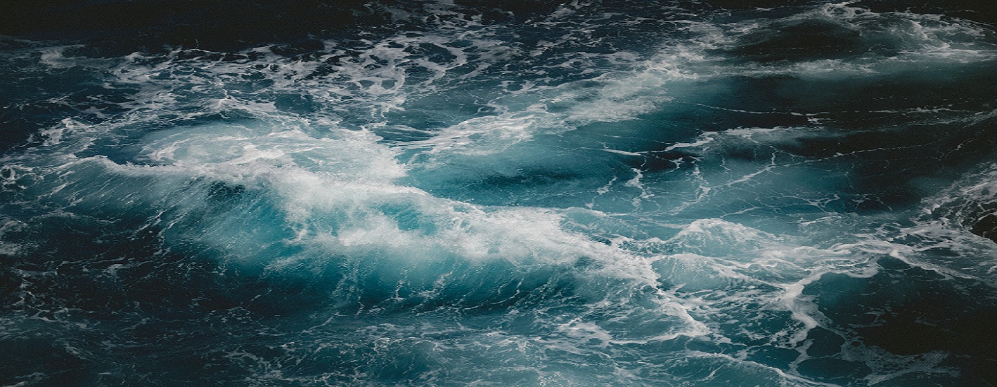 Close-up of churning ocean waves with white foam on dark blue water.