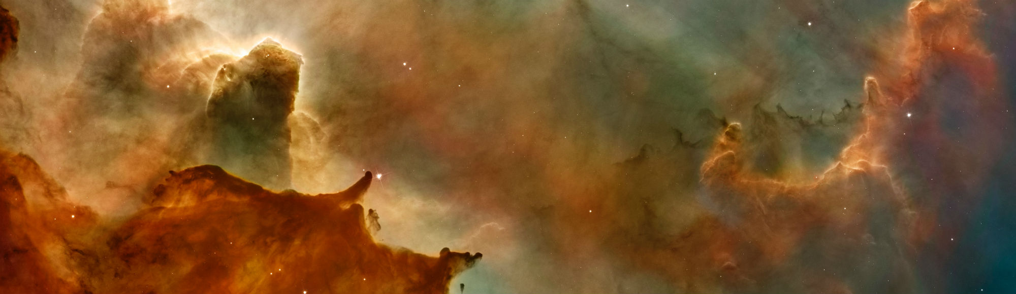 Panoramic image of a colorful nebula with glowing gas pillars, dust clouds, and scattered stars in space.