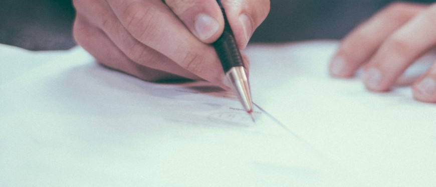 Close-up of a hand holding a pen over a piece of paper