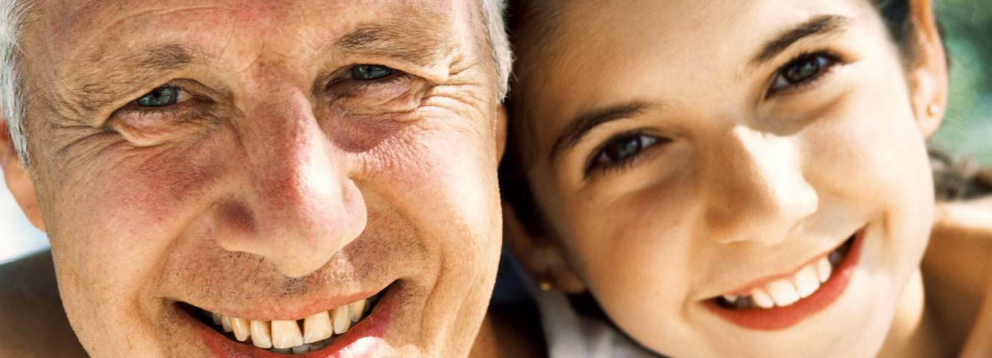 Close-up of an older man and a smiling girl side by side.