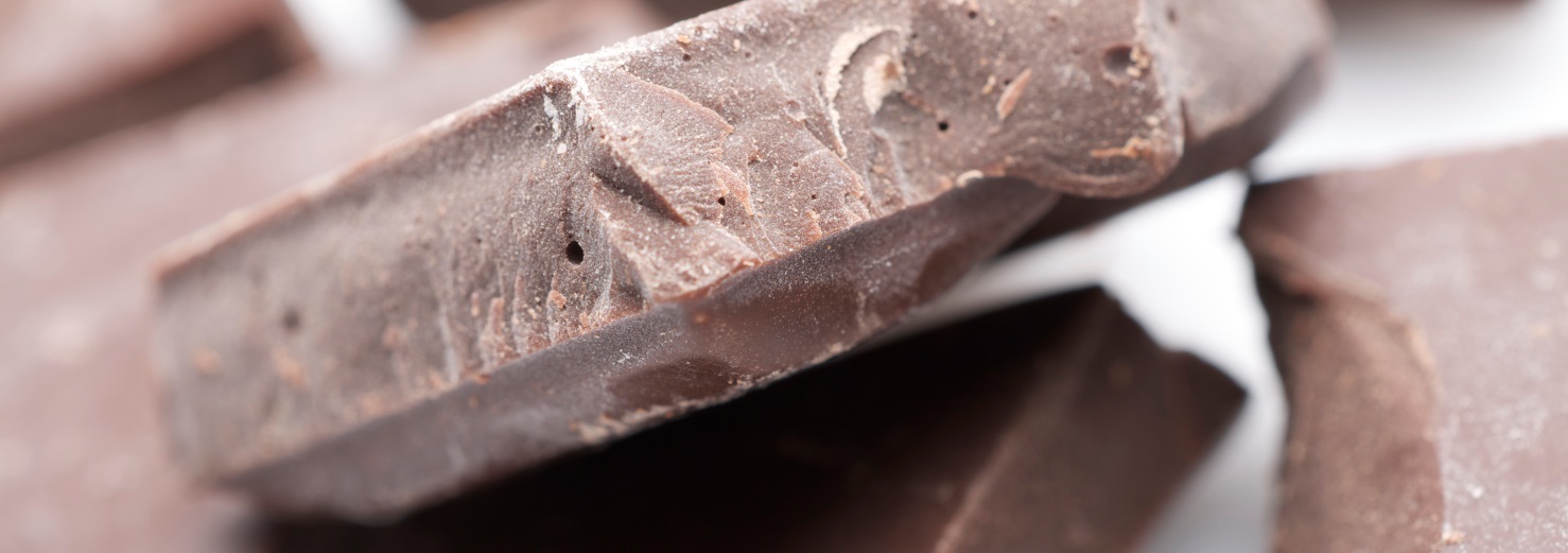 Nærbillede af flere stykker mørk chokolade med ru overflade og brudte kanter.