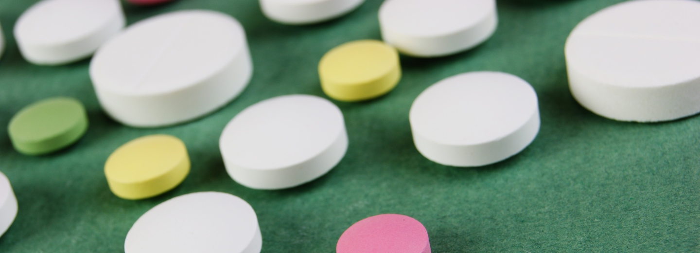 Assorted tablets in different colors scattered on a green surface.