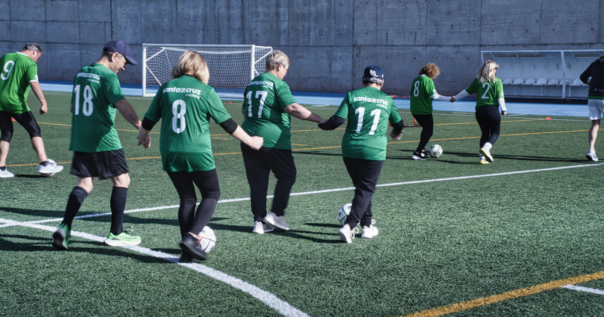 Billede af mennesker, der spiller fodbold i grønne bluser.