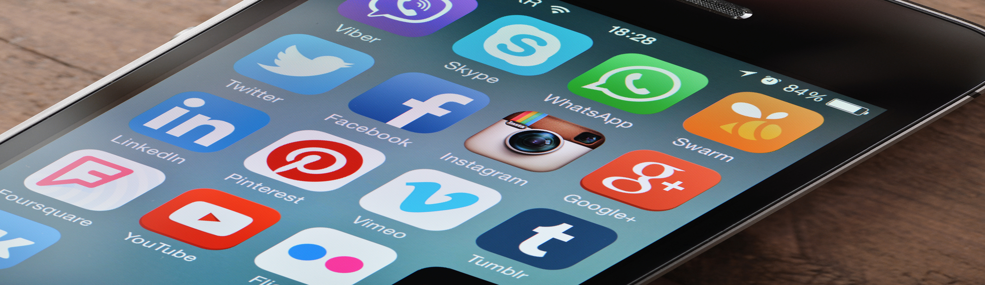 Nærbillede af en smartphone med sociale medie-apps som Twitter, Facebook, Instagram, WhatsApp, LinkedIn og YouTube på skærmen.