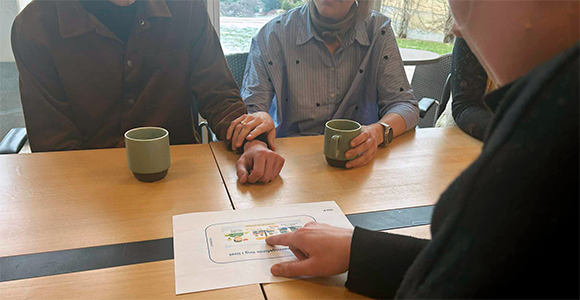 Afasiramt og pårørende sidder ved et bord med fagpersoner